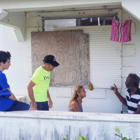 Team-speaking-with-barbudan-man-on-porch-of-damaged-home
